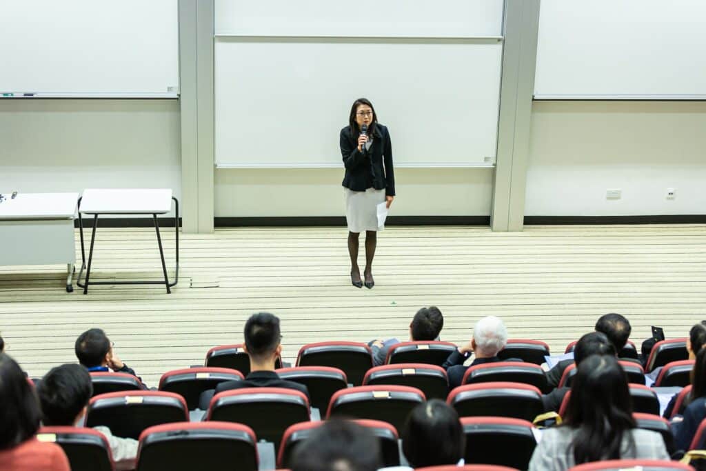 Femme tenant un micro s'exprimant devant une classe