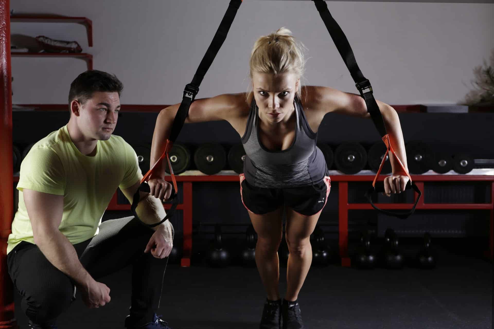 Une femme fait de l'exercice avec son coach à côté