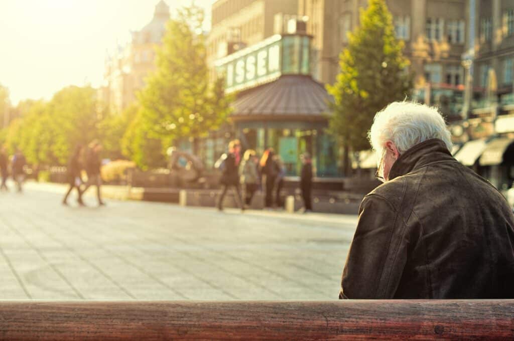 Personne âgée assis sur un banc portant une veste en cuir noir