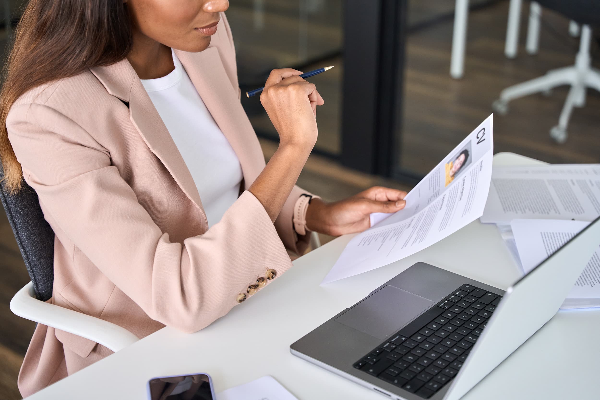 Recruteuse examinant un CV avec attention devant son ordinateur, illustrant le travail d’analyse réalisé par un cabinet de recrutement data pour sélectionner des profils qualifiés.