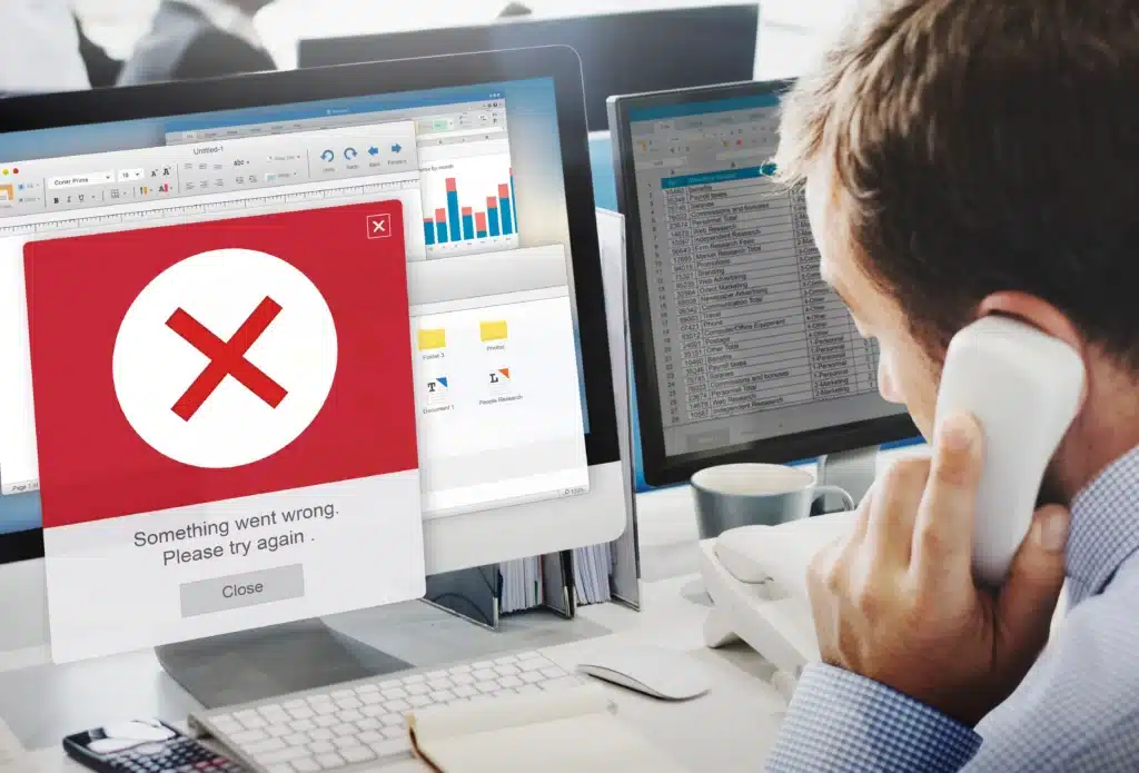 Employé des bureau regardant son écran d'ordinateur qui affiche une erreur indiquant une fuite de données ou une cybermenace.