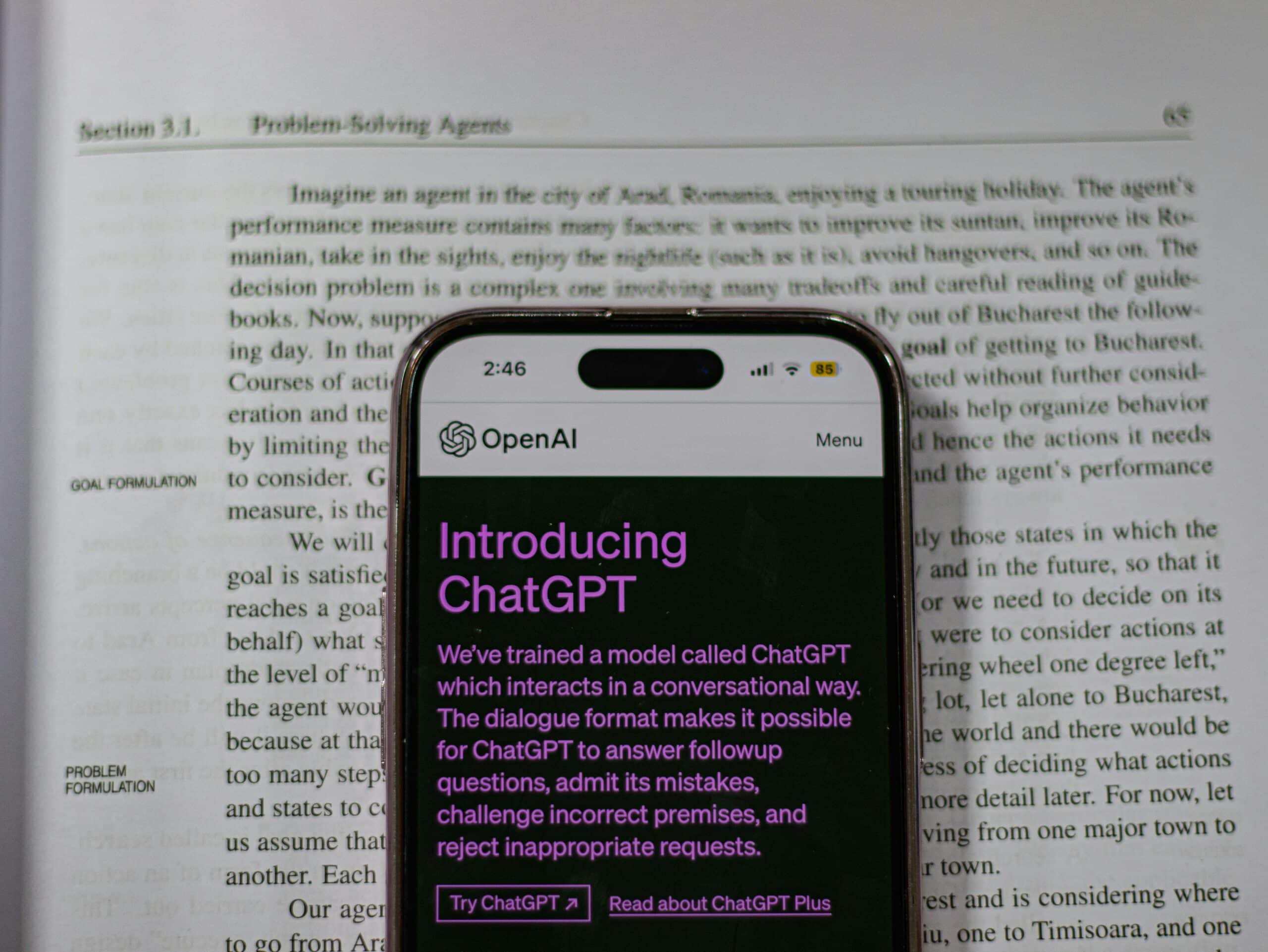 Mobile affichant la page de description du modèle d'IA GPT posé sur un livre ouvert pour illustrer la génération de texte.